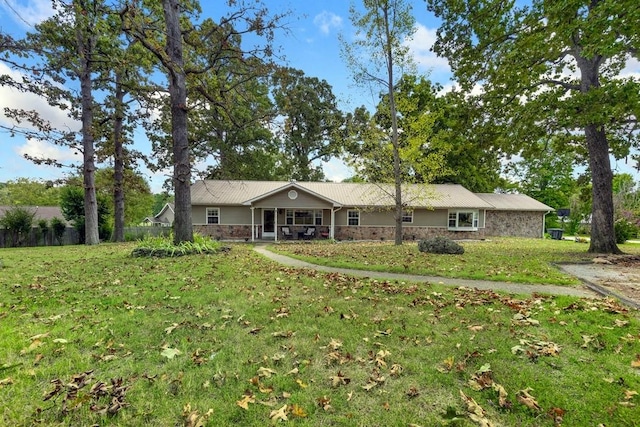 view of front of home featuring covered porch, a front lawn, and stone siding