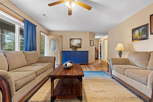 living area with light wood-style floors, ceiling fan, and visible vents