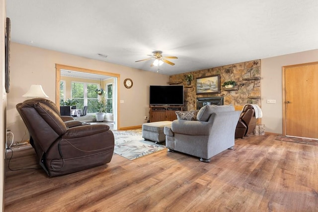 living area with baseboards, a ceiling fan, and light wood finished floors