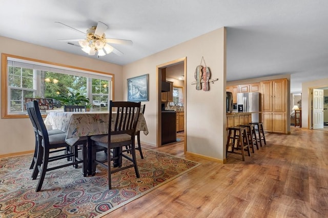 dining room with baseboards, a ceiling fan, and light wood finished floors