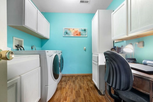 laundry room featuring wood finished floors, baseboards, cabinet space, and washing machine and dryer