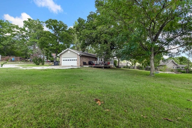 view of yard with a deck, fence, driveway, and a garage