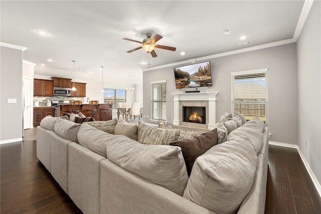 living room with ceiling fan, dark hardwood / wood-style flooring, a healthy amount of sunlight, and ornamental molding