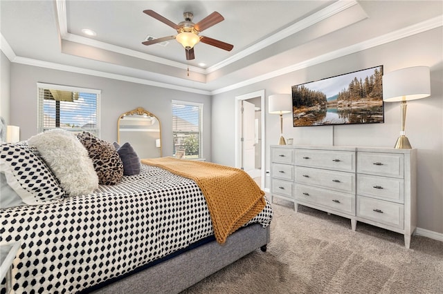 carpeted bedroom featuring a tray ceiling, connected bathroom, ceiling fan, and multiple windows