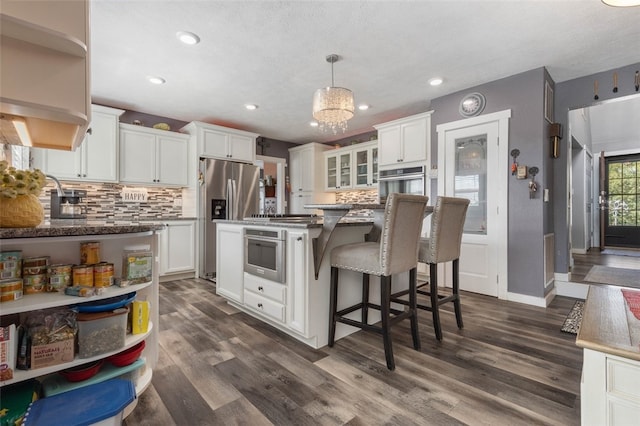 kitchen with pendant lighting, white cabinetry, stainless steel appliances, dark hardwood / wood-style floors, and a center island