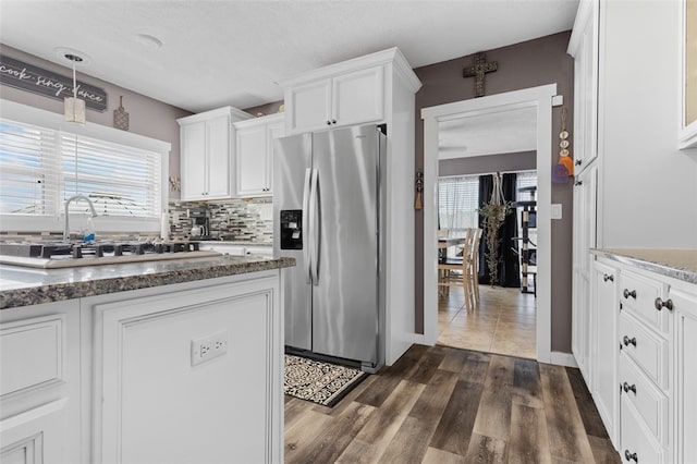 kitchen with dark stone countertops, white cabinets, backsplash, dark hardwood / wood-style floors, and stainless steel fridge with ice dispenser