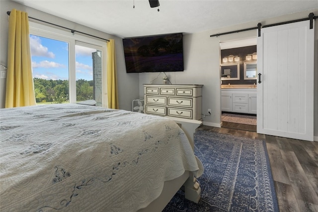 bedroom with ceiling fan, dark hardwood / wood-style floors, ensuite bathroom, and a barn door