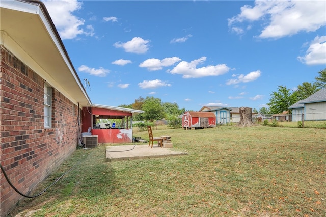 view of yard featuring a storage unit, a patio, and central AC unit