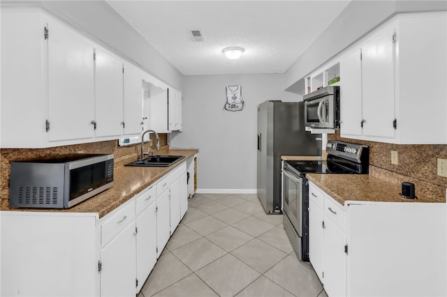 kitchen with white cabinets, sink, a textured ceiling, appliances with stainless steel finishes, and dark stone counters