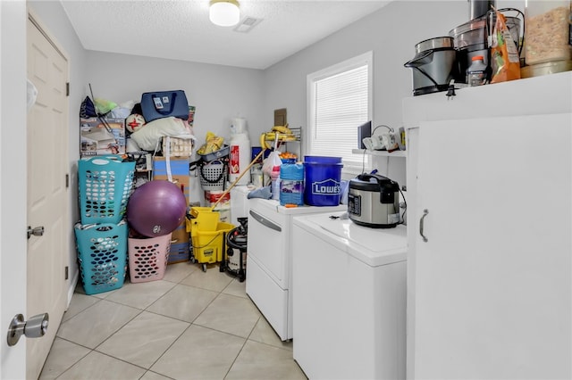 washroom featuring washing machine and clothes dryer, a textured ceiling, and light tile patterned flooring