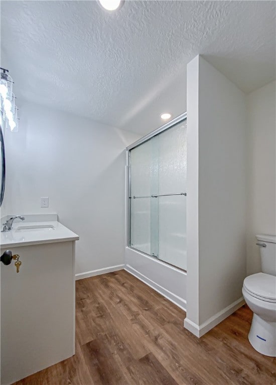 full bathroom with vanity, a textured ceiling, toilet, shower / bath combination with glass door, and hardwood / wood-style floors