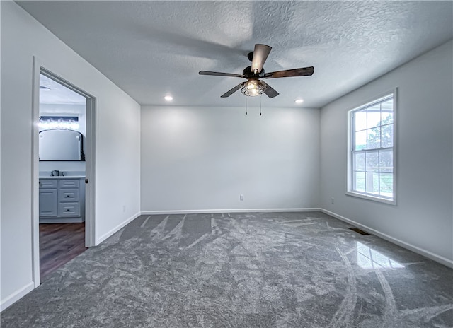 unfurnished room featuring a textured ceiling, dark carpet, and ceiling fan