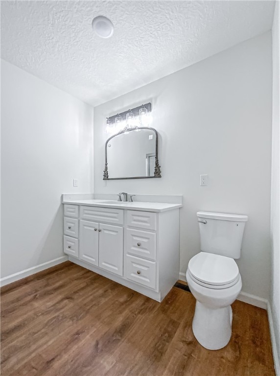 bathroom with vanity, toilet, a textured ceiling, and hardwood / wood-style flooring