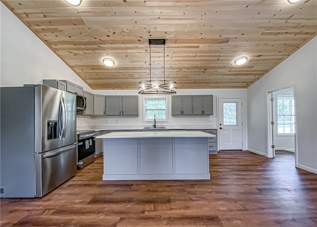 kitchen with dark wood-type flooring, sink, a kitchen island, appliances with stainless steel finishes, and decorative light fixtures