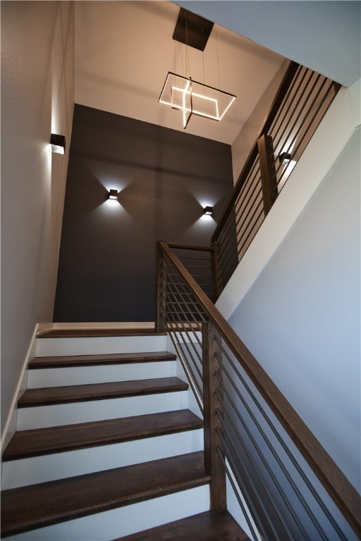 stairway featuring an inviting chandelier and hardwood / wood-style flooring