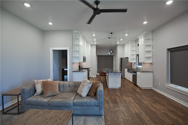 living room featuring ceiling fan, dark wood-type flooring, and sink