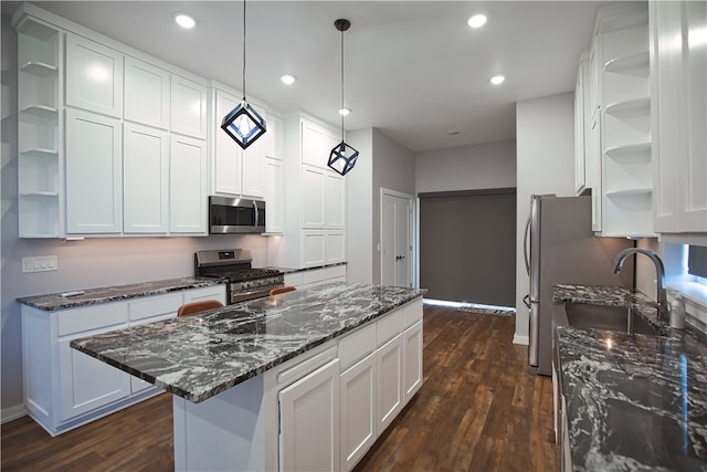 kitchen featuring dark wood-type flooring, sink, white cabinetry, hanging light fixtures, and appliances with stainless steel finishes