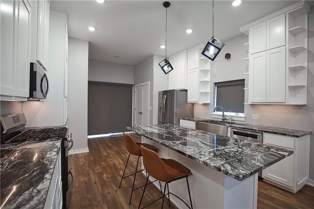 kitchen with dark stone countertops, white cabinetry, dark wood-type flooring, and stainless steel appliances