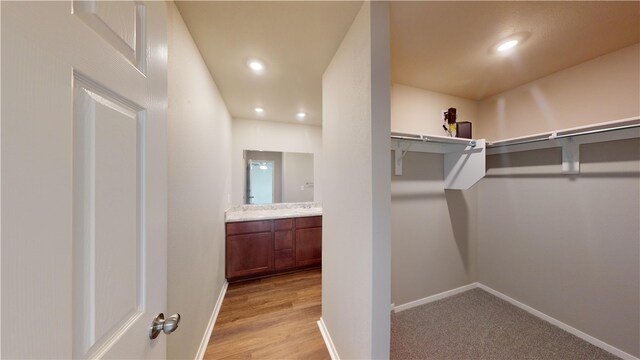 walk in closet with light hardwood / wood-style floors