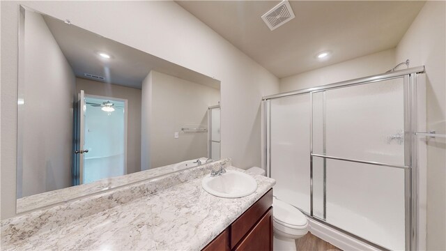 bathroom featuring vanity, wood-type flooring, ceiling fan, toilet, and an enclosed shower