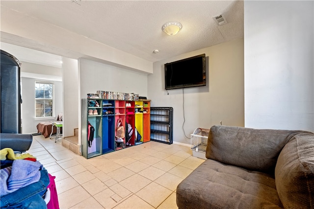 game room with a textured ceiling and light tile patterned floors