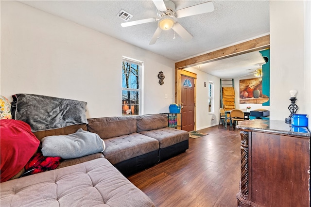 living room with ceiling fan, a textured ceiling, and dark hardwood / wood-style floors