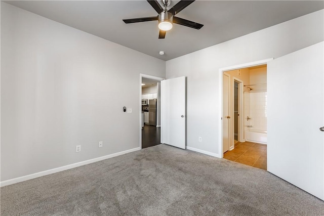 unfurnished bedroom featuring ceiling fan, light carpet, and connected bathroom