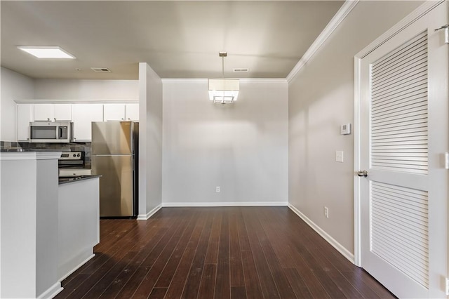 kitchen featuring dark wood-type flooring, pendant lighting, crown molding, white cabinetry, and appliances with stainless steel finishes