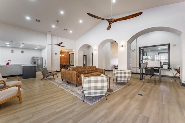 living room with light wood-type flooring, high vaulted ceiling, and ceiling fan