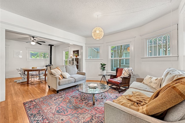 living room featuring ceiling fan, hardwood / wood-style flooring, a textured ceiling, and a wealth of natural light