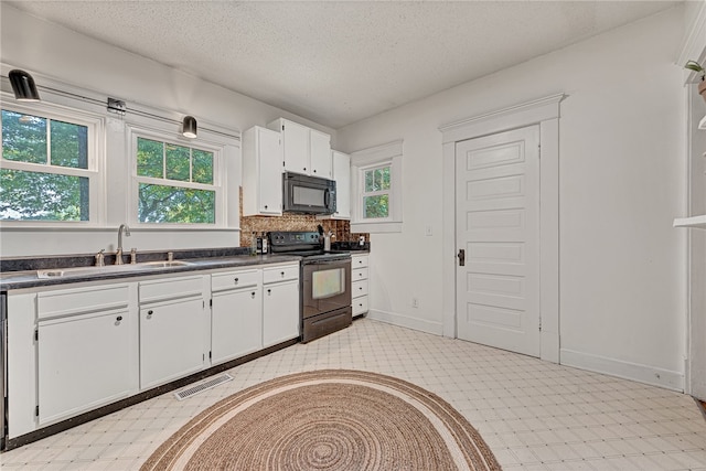 kitchen with a textured ceiling, black appliances, white cabinetry, and a wealth of natural light