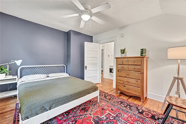 bedroom featuring vaulted ceiling, ceiling fan, hardwood / wood-style flooring, and a textured ceiling