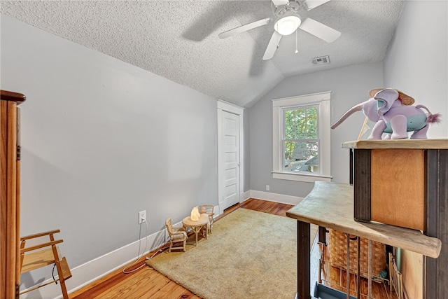 bedroom with lofted ceiling, ceiling fan, hardwood / wood-style floors, and a textured ceiling