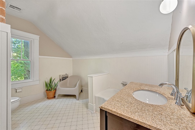 bathroom with lofted ceiling, wood walls, a tub, vanity, and toilet