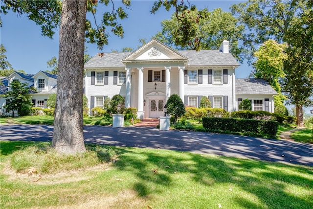 greek revival inspired property featuring a front yard and french doors