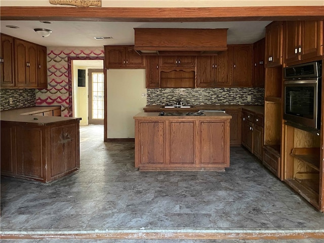 kitchen featuring decorative backsplash, stainless steel oven, and sink