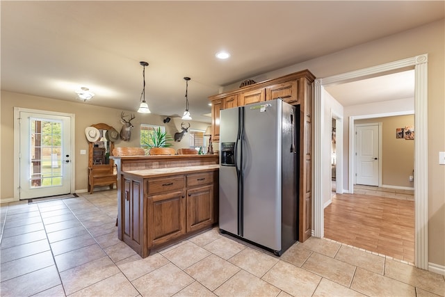 kitchen with pendant lighting, light wood-type flooring, kitchen peninsula, and stainless steel fridge with ice dispenser