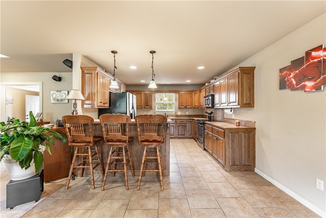 kitchen with appliances with stainless steel finishes, kitchen peninsula, pendant lighting, and a breakfast bar