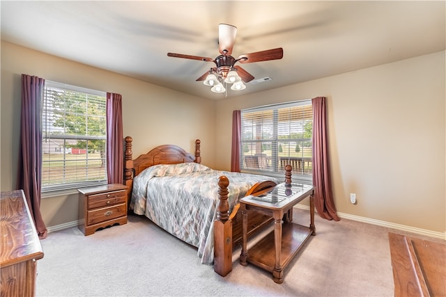 bedroom with multiple windows, light colored carpet, and ceiling fan