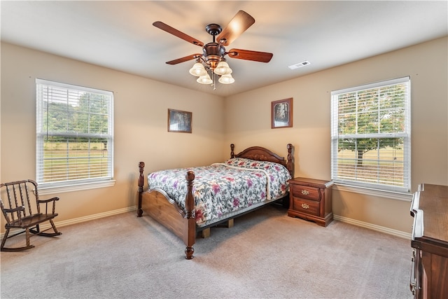 bedroom with ceiling fan, light colored carpet, and multiple windows