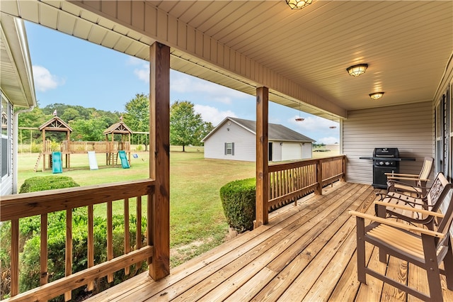 deck featuring a playground, a lawn, and a grill