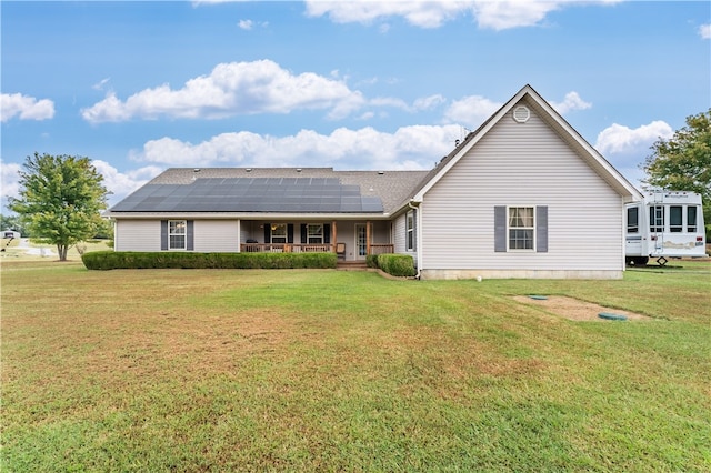 rear view of house with a yard, a porch, and solar panels