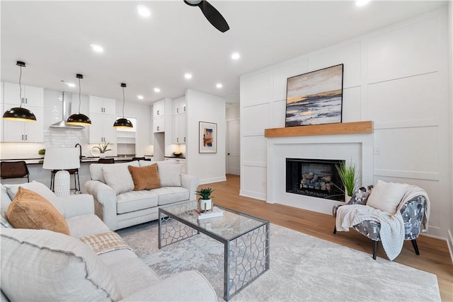 living room featuring light wood-type flooring, a fireplace, recessed lighting, and ceiling fan