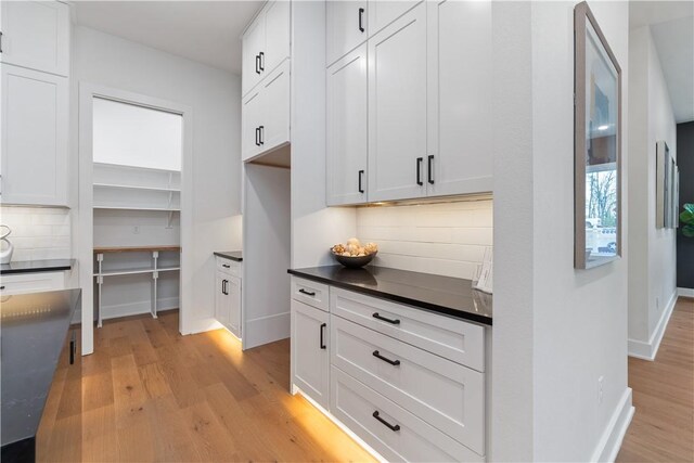 kitchen with dark countertops, light wood finished floors, baseboards, and decorative backsplash