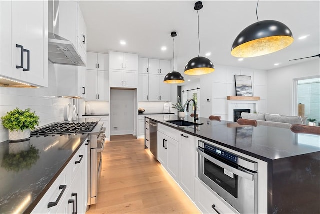 kitchen with a fireplace, light wood finished floors, decorative backsplash, and a sink