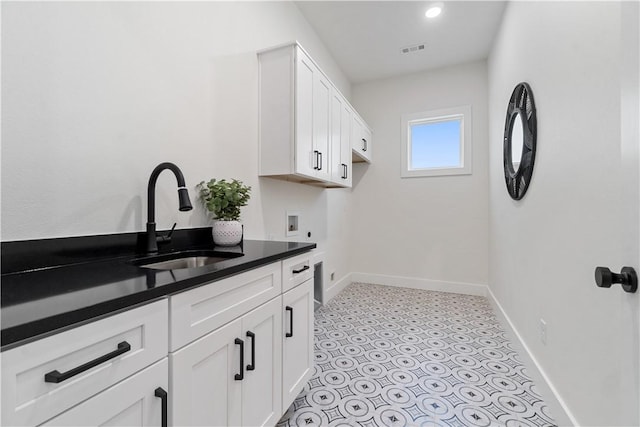 laundry room with light floors, visible vents, a sink, hookup for a washing machine, and baseboards