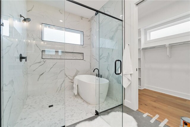 full bath with a freestanding tub and a marble finish shower