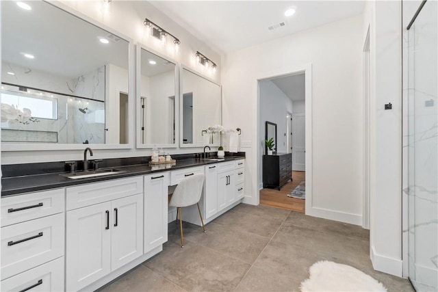 bathroom featuring double vanity, a marble finish shower, and a sink