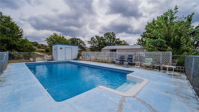 view of pool with a patio area and a shed