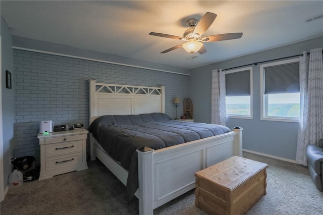 bedroom featuring dark carpet, ceiling fan, and brick wall